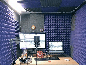 A desk setup with equipment for recording voice-overs inside of a WhisperRoom booth