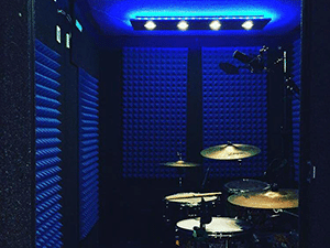 the interior of a WhisperRoom drum room with blue studio foam on the wall and a full drum kit