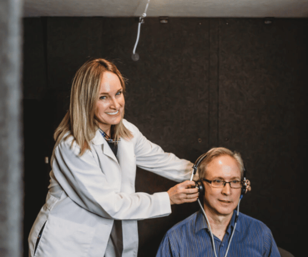 A woman audiologist performing a hearing test on an elderly man.