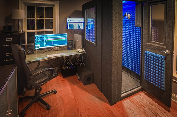 One of WhisperRoom's recording booths in a home studio with audio gear directly outside the wall window