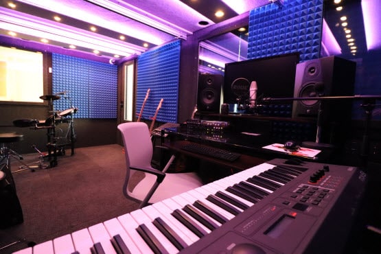 One of WhisperRoom's recording booths filled with a drumset, keyboard, guitars, and other recording gear