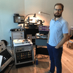 Mastering engineer Ryan Smith standing next to a collection of audio gear