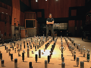 Alex Oana standing next to hundreds of microphones inside of a room