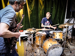 a drummer and guitarist playing music inside a room