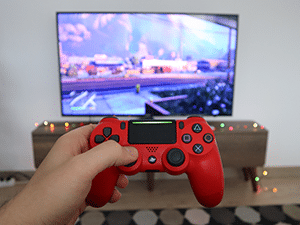 Hand holding video game controller in front of a TV