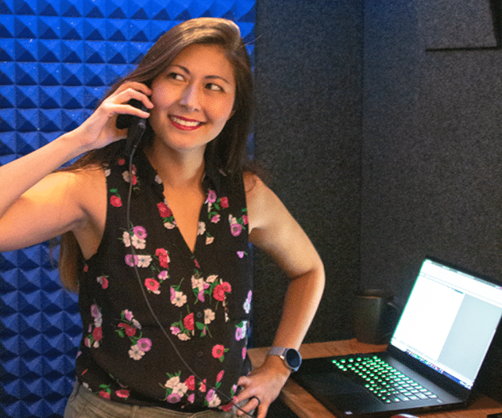 A woman engaged in a phone call inside a WhisperRoom Office Phone Booth. She is seen speaking on the phone while sitting next to a computer. The booth provides a private and sound-isolated environment for clear and uninterrupted communication.