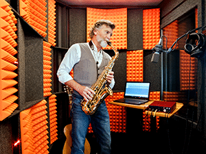 Image of a man recording saxophone inside of his WhisperRoom soundproof booth