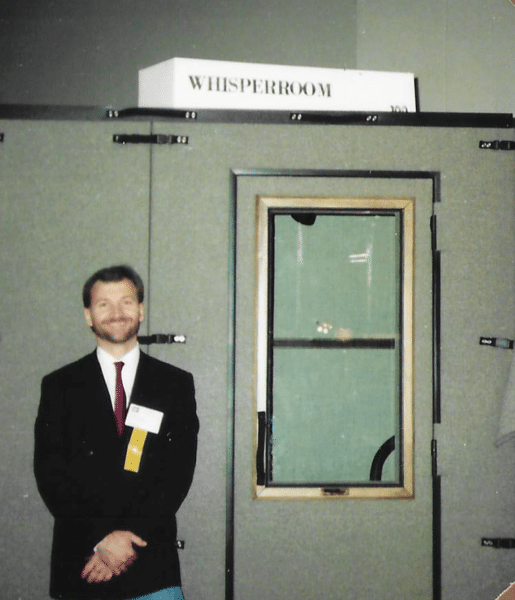 WhisperRoom's founder standing next to an original booth at a tradeshow