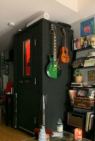 A WhisperRoom in an apartment with guitars hanging on the exterior wall.