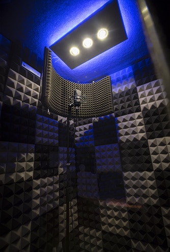 The interior of a WhisperRoom vocal booth with acoustic foam on all walls and a condenser mic.