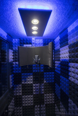 A WhisperRoom vocal booth with a blue studio light and a microphone setup inside the booth.