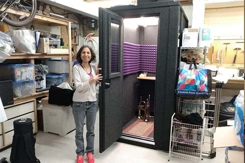A woman standing next to a WhisperRoom in her garage
