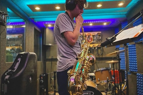 A saxophone player reading music inside of a WhisperRoom recording booth.