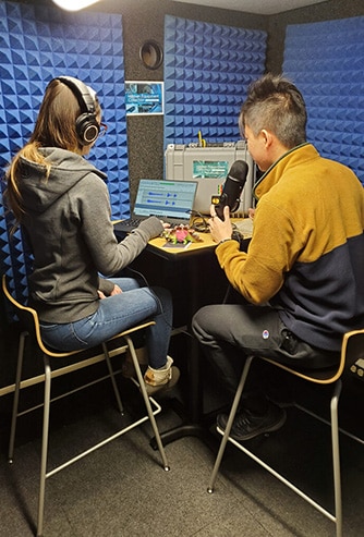 A young man and a young woman recording a podcast in the University of Pittsburgh's WhisperRoom vocal booth.