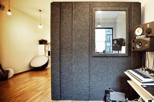 A WhisperRoom recording booth on a hardwood floor in a home recording studio
