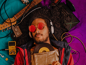 A man wearing headphone and listening to music with instruments around him