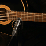A black acoustic guitar and a microphone for recording