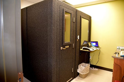 A WhisperRoom MDL 6084 S, a 5'x7' single-wall audiometric booth, is set up in an office for diagnostic hearing tests.