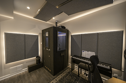 A WhisperRoom vocal booth in the corner of a production studio's room with several acoustic panels on the wall and ceiling.