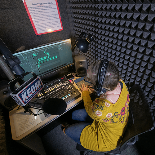 Podcast gear and a female student recording a podcast in KEOM's WhisperRoom.