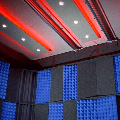 The interior of a WhisperRoom with red studio lights and the acoustic tuning package on the wall.