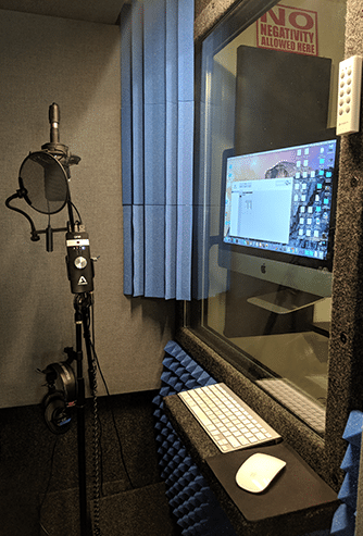 The inside of a WhisperRoom recording booth with a microphone, bass traps, and computer equipment.