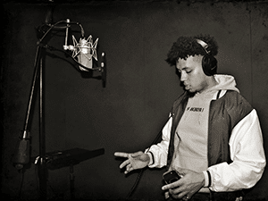 Young man wearing headphones prepares to record vocals into a condenser microphone