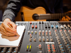 A musician writing a song at the mixing board in a recording studio