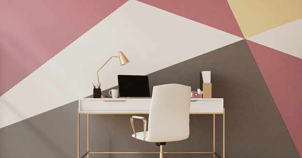 A workstation in a bedroom with multicolored geometric shapes painted on the wall.
