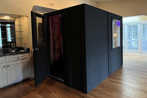 A WhisperRoom MDL 9696 S is shown from the outside of the sound booth inside of a residential home that has wood floors.