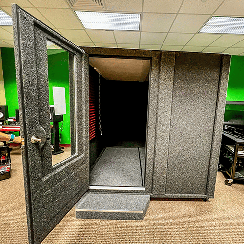 A WhisperRoom MDL 8484 S shown with an opened Wide-Access Door inside of a school's music lab.