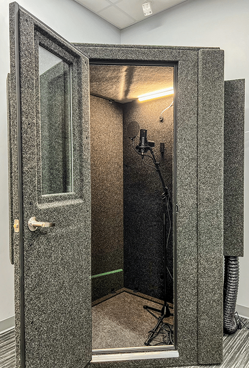 Exterior photo of a WhisperRoom MDL 127 LP S shown with the door open and a microphone on a stand inside the sound booth.