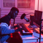 A man playing keyboard inside of a home recording studio.