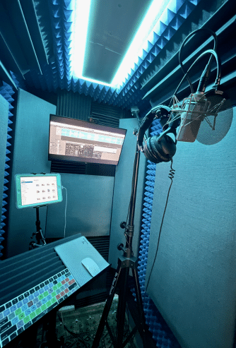 A look inside of Todd Stark's WhisperRoom MDL 4872 S with a condenser microphone, computer monitor, and music stand.