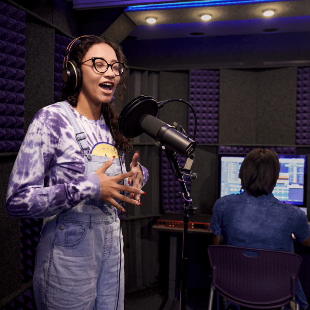 Female vocalist recording in GCU's recording lab, with a male operating the DAW in the background, showcasing WhisperRoom's versatility in educational, library, and various other institutional settings.