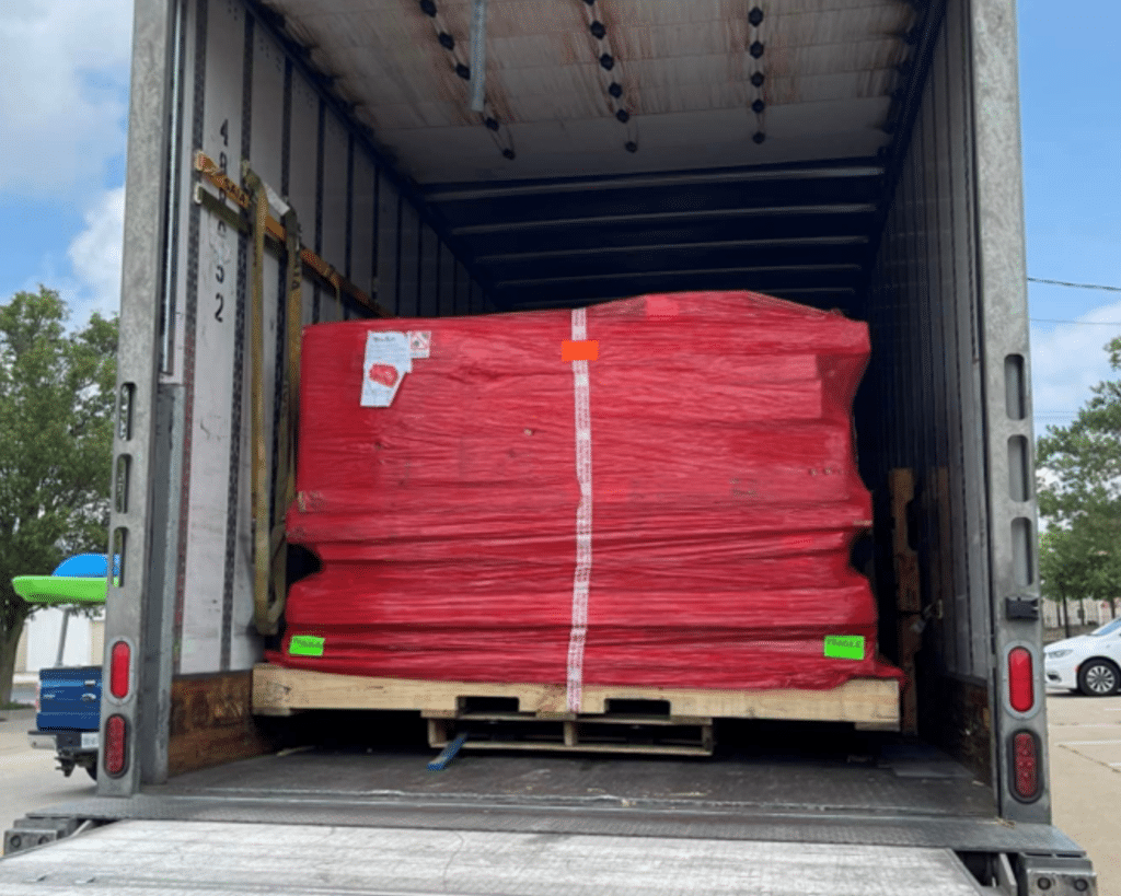 Image of a securely wrapped and packaged WhisperRoom shipment on a pallet, neatly positioned inside the back of a semi-truck, ready for delivery.