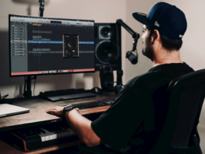 Man sitting at home studio recording desk, focused on digital audio workstation (DAW), showcasing the essence of home studio construction for musicians.